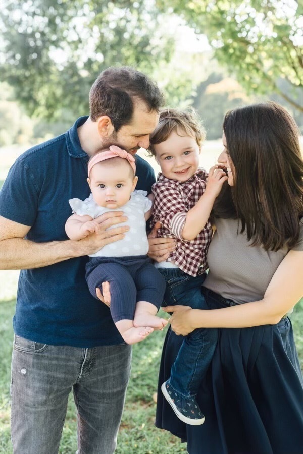 Ezra holding Lila and Leah holding Zeke in the park.